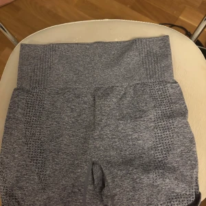 Grå sömlösa träningstights shorts - Snygga grå sömlösa shorts med hög midja och ventilerande mesh-detaljer längs sidorna. Perfekta för gymmet eller löprundan, sitter tight och bekvämt. Melerad grå färg och stretchigt material som formar sig efter kroppen.