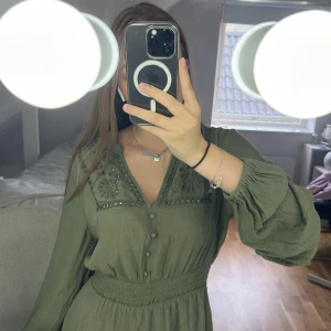 Olivgrön klänning från Zara!  - Supersöt olivgrön kort klänning från Zara med broderade detaljer. Klänningen har v-ringning, knappar framtill, långärmade puffärmar och markerad midja. Pris kan diskuteras 