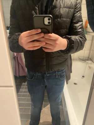 Svart pufferjacka från H&M - Svart pufferjacka från H&M med quiltad design och dragkedja framtill. Jackan har långärmade ärmar och en klassisk krage. Materialet är syntet och polyester, vilket gör den lätt och smidig. Perfekt för dig som gillar en clean och enkel stil.