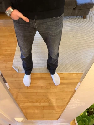 Mörkgrå jeans från Hugo Boss - W33/L36. Säljer ett par mörkgrå jeans från Hugo Boss med klassisk femficksdesign och diskret tvätt. Jeansen har rak passform och normal midja, tillverkade i mjuk bomullsdenim med snyggt Boss-läderpatch bak i midjan. Perfekta för en clean och stilren look.