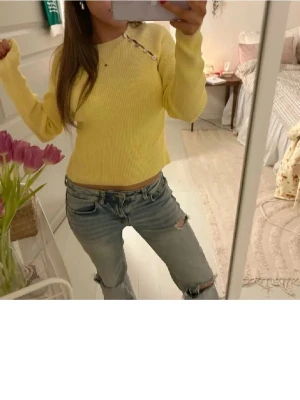 Gul tröja  - tröjan är i M men passar mig som är xs/s Snygg gul stickad tröja med ribbad struktur och dekorativa knappar längs axeln. Modellen är croppad och har långa ärmar, perfekt för dig som gillar färg och vill ha en trendig look. Passar till jeans eller kjol för en cool stil.