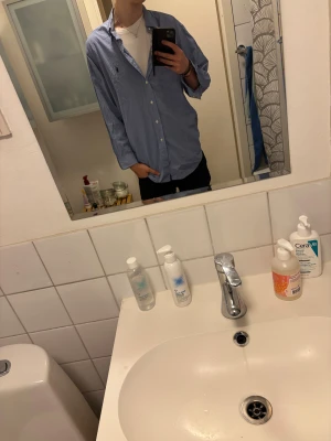 Blå skjorta från Ralph Lauren - Säljer en klassisk blå skjorta från Ralph Lauren med broderad logga på bröstet. Skjortan är i storlek 16 1/2 eller 32/33. Osäker på vad det motsvarar men verkar passa som en XL