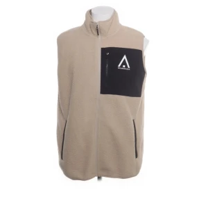 Beige fleeceväst från WearColour - Beige fleeceväst med svart bröstficka och vit logga från WearColour. Västen har hel dragkedja framtill, två sidofickor med dragkedja och hög krage. Perfekt för lager-på-lager och chill stil. Snygg kontrast mellan beige och svart. 