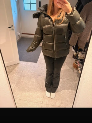 Mörkgrön pufferjacka med huva från Massimo dutti - Säljer en mörkgrön pufferjacka med huva och dragkedja framtill från Massimo dutti. Jackan har två sidofickor med dragkedja och en quiltad design som ger en snygg och puffig look. Perfekt för kalla dagar och riktigt skön att bära.