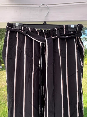 Randiga flowy byxor från H&M - Ett par randiga byxor som är lite kortare.  Stretchband i midjan + knytband. Sparsamt använda, storlek 40 🤎  Innerbenslängd: 65 cm Midja: 77 cm