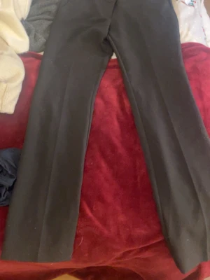 Svarta kostymbyxor bootcut  lowwaist  - Snygga svarta kostymbyxor. Perfekta för en clean och stilren look. Materialet känns mjukt och har en lätt stretch för extra komfort. Passar dig som gillar enkel och tidlös stil. Är lite noppriga men de är ändå fina. Storlek 38 men passar 36