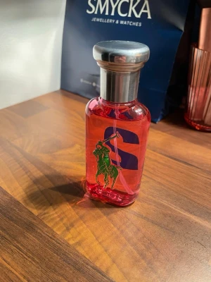 Ralph Lauren Big Pony 2 Parfym - Cool parfym med färgstark design och ikonisk polo-logga. Perfekt för dig som vill sticka ut och addera en sportig touch till din stil. Flaskan har en tydlig siffra 2 och röd färg.