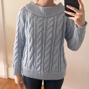 Ljusblå kabelstickad tröja NA-KD - Superfin ljusblå kabelstickad tröja från NA-KD med bred ribbad krage och muddar. Tröjan har ett klassiskt flätmönster och är långärmad. 