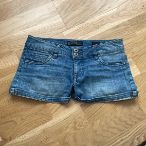 Blå jeansshorts från ONLY - Snygga blå jeansshorts från ONLY med klassisk femficksdesign, dubbla knappar och bälteshällor. Shortsen har en lågmidjad passform och är tillverkade i slitstarkt bomullsmaterial. 