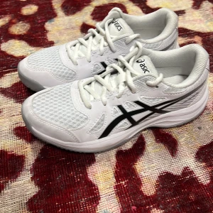 Vita Asics sneakers med svart detalj - Säljer ett par fräscha vita Asics sneakers i storlek 35. Skorna har svart Asics-logga på sidorna, snörning och meshpaneler för extra andningsförmåga. Snygg sportig look och bekväm passform, perfekta för träning eller chill vardagsstil.