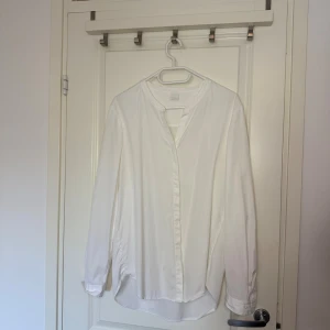 Vit henley-skjorta från BOSS Orange - Säljer en stilren vit henley-skjorta från BOSS Orange. Skjortan har lång ärm, rund halsringning och knappar framtill. Tillverkad i mjuk bomull för en clean och fräsch look. Perfekt för dig som gillar minimalistisk stil och vill ha något klassiskt i garderoben.