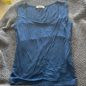 Blå linnetopp från Batik - En enkel och stilren blå linnetopp från Batik. Toppen är ärmlös med rundad halsringning och har en mjuk, slät känsla. Perfekt att matcha med jeans eller kjol för en avslappnad look.