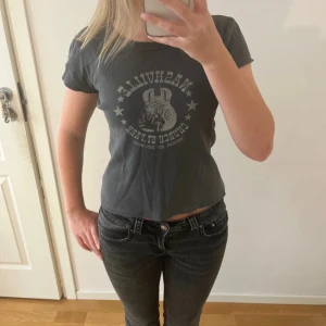 Svart Nashville t-shirt croppad - Cool svart t-shirt från You Get med Nashville-tryck och gitarrmotiv framtill. Modellen är croppad med korta ärmar och rund halsringning. Perfekt för dig som gillar en avslappnad och trendig stil.