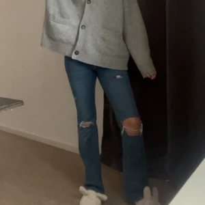 Blå bootcut jeans från gina🌸 - Säljer ett par blå bootcut jeans från gina i storlek 38. Jeansen har slitna detaljer och hål vid knäna för en trendig look. Perfekta för dig som gillar en avslappnad men snygg stil.