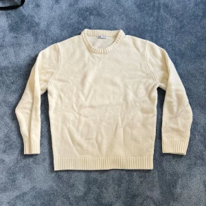 Krämvit stickad tröja från Zara - En stilren krämvit stickad tröja från Zara med rund halsringning och ribbade muddar. Perfekt för lager-på-lager och enkel att matcha med jeans eller kjol. Klassisk modell med lång ärm och mjukt material.