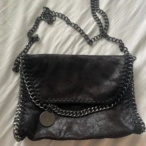 Svart axelväska - Svart axelremsväska med grå/mörk silvrig kedja. Använd några gånger