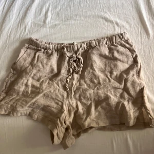 Beiga linneshorts från Gina Tricot XS - Säljer ett par beiga shorts från Gina Tricot i storlek XS. De är gjorda i svalt linne och har en avslappnad passform och snörning i midjan. Perfekta för varma dagar och riktigt sköna att ha på sig. Dom ser skrynkliga ut för jag knappt använt dom