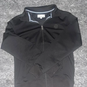 Stone Island Ziptröja - Svart ziptröja från Stone Island i bomull med broderad logga på bröstet. Tröjan har ståkrage, hel dragkedja och ribbade muddar. Snygg och stilren modell, aldrig använd. 