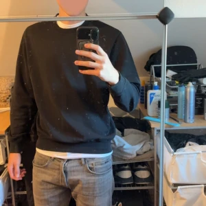 Svart sweatshirt från Weekday - En stilren svart sweatshirt från Weekday i klassisk modell. Tröjan har rund halsringning, ribbade muddar vid ärmslut och nederkant samt är tillverkad i mjuk bomullsmix. Perfekt för en clean och avslappnad look.