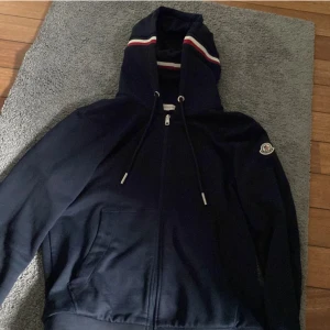 Mörkblå Moncler hoodiejacka med dragkedja - Tja säljer denna feta Moncler hoodie i storlek L. Riktigt snygg och skön att ha på sig👍Skick är väldigt bra inga skador. Hör av dig om du är intresserad!😁