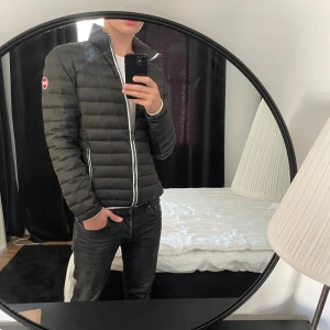 Svart pufferjacka från Colmar - Säljer en svart pufferjacka från Colmar med vit dragkedja och logga på ärmen. Jackan har quiltad design, hög krage och två fickor med dragkedja. Insidan är grön och materialet är lätt och syntetiskt, perfekt för kyliga dagar. Pris ej hugget i sten.