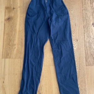 Mörkblå chinos från Jack & Jones - Snygga mörkblå chinos från Jack & Jones i slim fit-modell. Byxorna har klassisk knappstängning, bälteshällor och är tillverkade i mjuk bomull. Perfekta för en clean och stilren look.