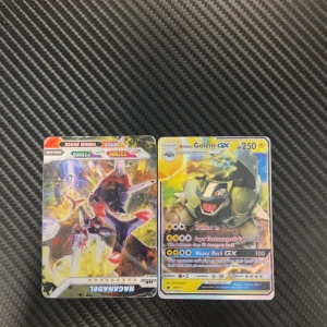 Pokémon-kort: Naganadel & Alolan Golem GX - Två coola Pokémon-kort med Naganadel och Alolan Golem GX, perfekta för samlare och fans av Pokémon! Färgstarka och glansiga kort som ger din samling extra power och stil. Passar dig som gillar spel, strategi och att bygga ditt eget Pokémon-team. JAG VET INTE OM DE ÄR ÄKTA !!!