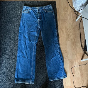 Blå high waist jeans från Just Junkies - Säljer ett par blå jeans från Just Junkies med hög midja och extra loose bootcut. Modellen har riktigt loose ben och klassisk femficksdesign. Materialet är robust denim och färgen är en snygg mellanblå ton. Perfekt för dig som gillar avslappnad och bred siluett.