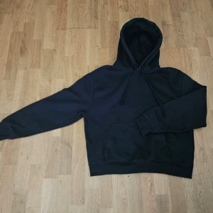 Svart hoodie från Zara - En svart hoodie från Zara i storlek M. Klassisk modell med huva och dragsnören, samt en stor magficka framtill. Tröjan har långa ärmar och ribbade muddar vid ärmslut och nederkant. Perfekt för en chill och avslappnad stil.