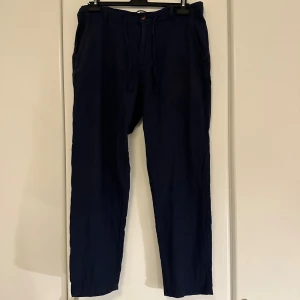 Mörkblå linnebyxor Selected Homme - Snygga mörkblå linnebyxor från Selected Homme med avslappnad passform och dragsko i midjan. Byxorna har sidfickor, bakfickor med knapp och är perfekta för en chill och stilren look. Materialet är linne vilket gör dem luftiga och sköna.