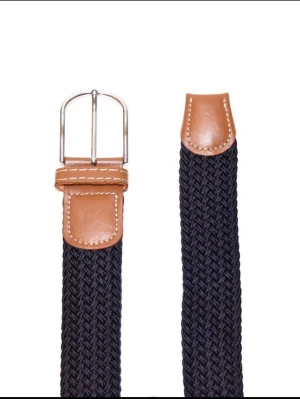 Flätat ”grisch” bälte - Navy  - Snyggt och funktionellt flätat bälte från Montore, perfekt för både vardag och mer uppklädda outfits. Det elastiska materialet ger en bekväm passform och gör att bältet sitter bra hela dagen, oavsett tillfälle. Klassisk design med detaljer i konstläder och metallspänne som passar lika bra till jeans, chinos eller kostymbyxor. Bältet är justerbart utan fasta hål tack vare den flätade strukturen, vilket ger extra flexibilitet och komfort. Vid fler frågor, tveka inte att kontakta oss🤝✅