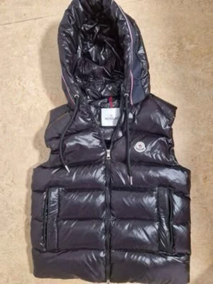 Svart dunväst från Moncler - Säljer en svart, glansig dunväst från Moncler. Västen har två fickor med dragkedja och Moncler logga på bröstet. Perfekt för lager på lager och riktigt snygg till höst och vinter.