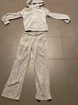 Juicy couture sett!! - SUPER MYSIGT Juicy Couture. Byxorna har normal passform, raka ben och resår i midjan med snörning. Tillverkade i mjuk velour som känns riktigt skön mot huden. Perfekta för chill dagar eller när du vill ha en avslappnad look. Tröjan har ett fint jc märke. Byxorna är väl andvända , tröjan använd en gång
