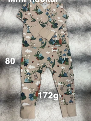 Beige byxdress med naturmönster, stl 80 - Supersöt beige byxdress med tryck av sniglar, svampar, blommor och moln i grönt, blått och rött. muddar vid benslut. Perfekt för lek och mysiga dagar.🌸 Sparsamt använd. Små svaga fläckar. Storlek 80