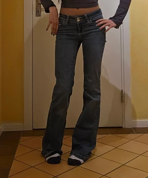 Blå bootcut jeans med låg midja NELLY - ❗️Skriv innan köp❗️Säljer ett par blå jeans med bootcut och låg midja. Jeansen har vita kontrastsömmar och detaljer på bakfickorna. Passformen är tajt och materialet är stretchigt jeans. Använt ett fåtal ggr och köpta i butik. Midjemått: 34cm