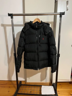 Ralph Lauren jacka - Helt ny Ralph Lauren jacka, 10/10 skick. Den är endast använd en gång och nu inser jag att den inte kommer till användning så därför säljer jag den, jackan är som ny. Det är storlek M, sitter som en vanlig M jacka. Det är svart färg på den. Riktigt varm och bekväm inför vintern, hör av er vid frågor och funderingar! Väldigt billig vinterjacka, missa inte chansen!