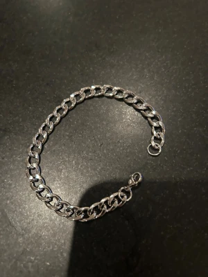Kedjearmband i silverfärg 19cm  - Stilrent kedjearmband i silverfärg med breda, platta länkar. Perfekt accessoar för att ge din outfit en cool och modern touch. Armbandet har ett klassiskt lås och passar både till enkla och mer uttrycksfulla stilar.