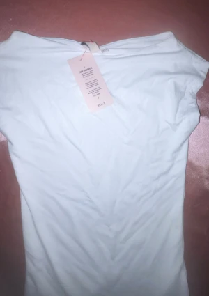 Vit ärmlös topp från Nelly XS - Säljer en stilren vit topp från Nelly i storlek XS. Toppen är ärmlös med en enkel, rak passform och tillverkad i mjukt material som känns skönt mot huden. Perfekt att matcha med jeans eller kjol för en clean look.
