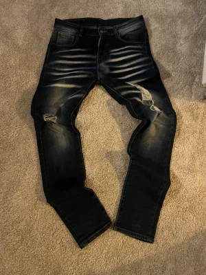 Dsquared2 jeans - Säljer ett par dsqured2 jeans i mörkblå tvätt med slitningar och snygga detaljer på framsidan. Jeansen har klassisk femficksdesign, gul dsquared-lapp bak och är tillverkade i stretchigt jeanstyg för skön passform. Passformen är så sjukt snygg. Säljer för den är för liten på mig. Storlek 31 men passar 32 och 33