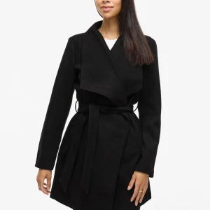 Svart kappa från Vila - Svart kappa från Vila med snygg omlottkrage och bälte i midjan. Jackan har lång ärm och stilren design som ger en clean look. Materialet är mjukt och känns lyxigt, perfekt för dig som gillar minimalistisk stil. Passformen är normal och längden går till strax ovanför knä. Säljer igen då tidigare köpare ångrats sig. Ligger på 600kr och säljer om för 399kr