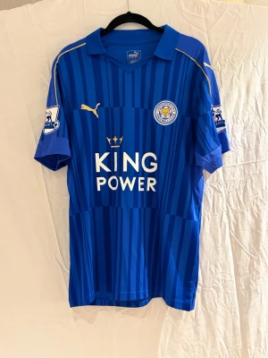 Leicester City 16/17 Vardy #9 fotbollströja - Blå randig Leicester City fotbollströja  med Vardy och nummer 9 på ryggen. Premier League-patch på ärmen, klubbmärke på bröstet och King Power-tryck framtill. Tillverkad i lätt polyester med gulddetaljer längs axlarna.