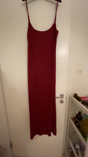 Vinröd långklänning med smala axelband - Säljer en stilren vinröd långklänning med smala axelband och stretchig passform från shein. Klänningen har en enkel design utan detaljer och ärmlös modell, perfekt för dig som gillar minimalistisk stil. Materialet känns mjukt och följsamt mot kroppen.