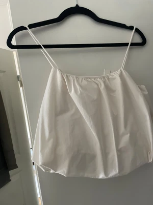 Vit linnetopp från H&M med tunna band - Säljer en fräsch vit linnetopp från H&M i storlek S. Toppen har tunna axelband och en luftig, rak passform som ger en chill vibe. Perfekt för varma dagar och enkel att matcha med jeans eller shorts. Materialet känns mjukt och lätt mot huden.