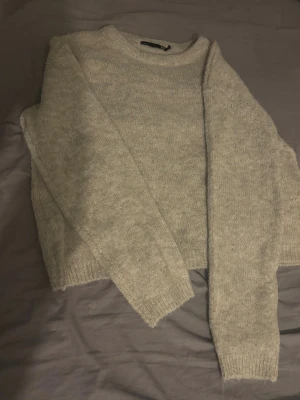 Beige stickad tröja från 157 XS - Mysig beige stickad tröja från 157 i storlek XS. Tröjan har rund hals och långa ärmar med ribbade muddar vid ärmslut och nederkant. Perfekt för att hålla sig varm under kyliga dagar och har en enkel, clean look.