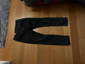 Levi's 502 svarta jeans med rå kant - Svarta Levi's Premium 502 jeans med rak passform och croppad längd. Jeansen har rå, avklippt kant vid benslut för en edgy vibe. Klassisk femficksmodell med Levi's läderpatch bak. Tillverkade i slitstark denim.