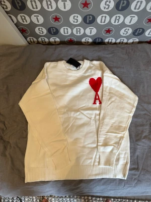 Vit stickad tröja från Ami Paris - Säljer en vit stickad tröja från Ami Paris med röd hjärt logga. Helt oanvänd. Födelsedags present till mig men den va alldeles för stor.