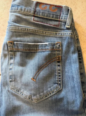 Blå skinny jeans från Dondup, stl 33 - Snygga blå jeans från Dondup i storlek 33. Modellen har klassisk femficksdesign, smal passform och coola detaljer som broderad bakficka och metallknapp med logga. Jeansen är gjorda i mjukt denimtyg med lätt tvättad look och kontrastsömmar.