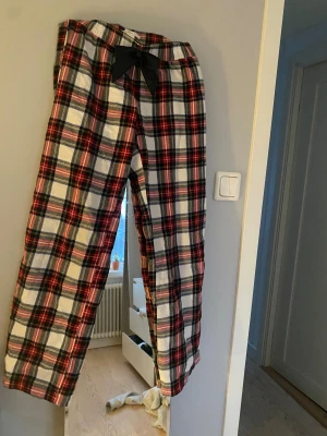 Rutig pyjamasbyxa med rosett - Mysiga pyjamasbyxor i röd, vit och mörkblå rutig bomull med svart rosett. Från Gina tricot i st: 146/152💌