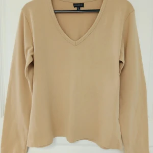 V-ringad långärmad tröja - En stilren beige långärmad tröja med v-ringning. Tröjan har en clean design och är tillverkad i mjuk bomull (95 %) och elastisk elastan (5 %). Perfekt för dig som gillar minimalistiska och neutrala plagg. Tröjan har naturligtvis tvättats. Se bilder för skick och passform. Storlek 42/44 enligt lappen men då måttet armhåla till armhåla är cirka 48 cm så stämmer 42 bättre. Axelsöm till ärmslut är cirka 57-58 cm. Tvättas i 40 grader.