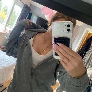 Grå hoodie från Puma med dragkedja - Säljer en grå hoodie från Puma med svart logga på bröstet. Tröjan har dragkedja, huva med snörning och två fickor framtill. Använd fåtal gånger!